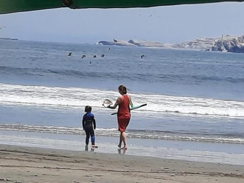 a woman and a child standing on the beach at Bungalows Cerro Azul in Cerro Azul