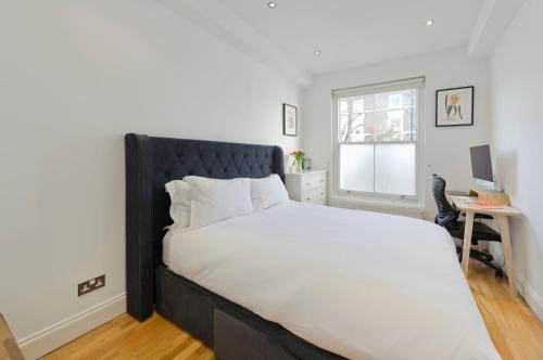 a bedroom with a large bed with a black headboard at Veeve - East London Light in London