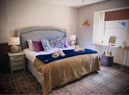Abernethy的住宿－The Crees Room only，一间卧室配有一张大床,提供紫色和蓝色枕头