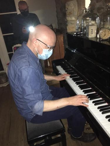 a man wearing a face mask playing a piano at Maison Jules in Sainte-Ode