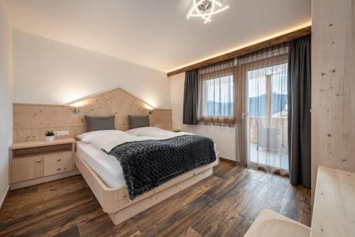 une chambre avec un grand lit et une grande fenêtre dans l'établissement Obergasserhof, à Rodengo