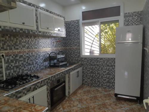 a kitchen with a stove and a white refrigerator at VILLA MODERNE in Tahla