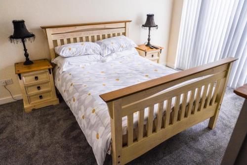 um quarto com uma cama de madeira e duas mesas de cabeceira em Shepherd's Rest Apartments Central Location With Parking em Tewkesbury