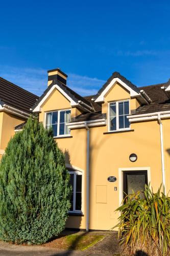 a yellow house with a tree in front of it at 21 Killarney Holiday Village in Killarney