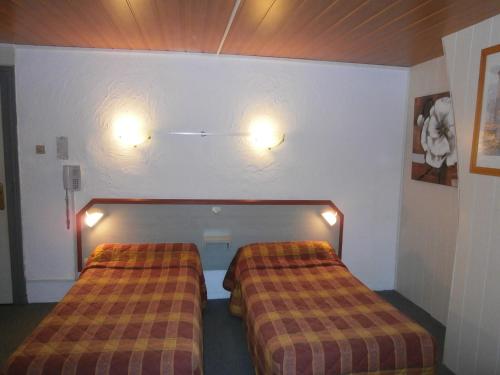 two beds in a room with lights on the wall at Hotel Beausejour in Rouen