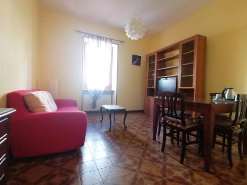 a living room with a red couch and a table at Due finestre sul cortile in Novi Ligure