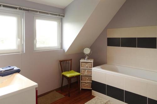 a bathroom with a tub and a chair and windows at Holiday Home in Bréhal near Sandy Beach in Bréhal