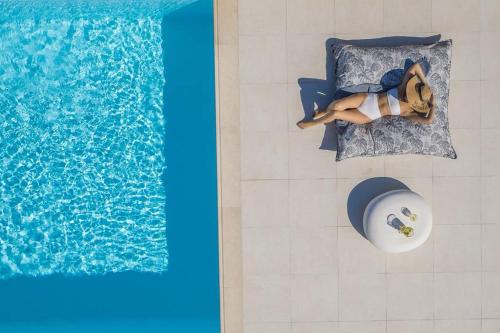 a woman laying on a bed next to a swimming pool at Soleila Mykonos Villa in Kalafatis