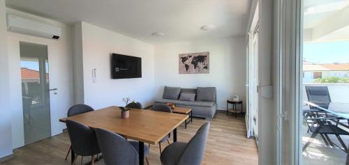 ein Esszimmer mit einem Tisch, Stühlen und einem Sofa in der Unterkunft Aquarius Luxury apartment with pool and sea view in Novalja