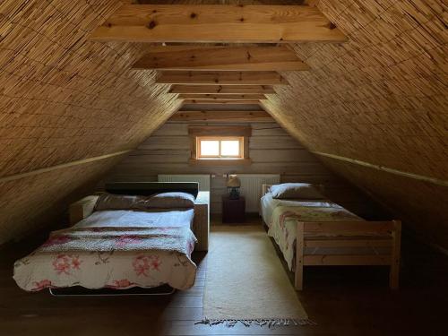 a attic room with two beds and a window at Baublys Lake Lodge in Viktarinas