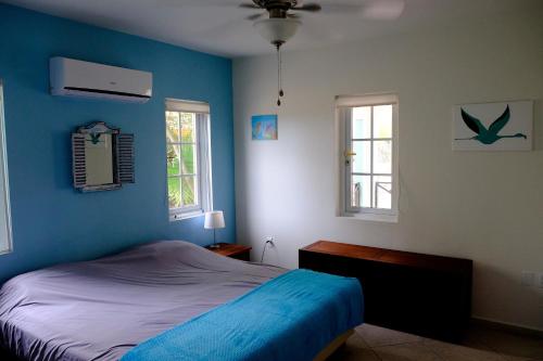 a blue bedroom with a bed and two windows at Villa Olivia Poolside in Kralendijk