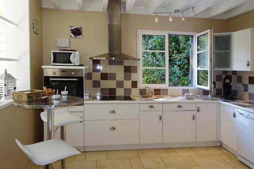 une cuisine avec des armoires blanches et une table avec un micro-ondes dans l'établissement Charming House in Normandy near White Coast, à Vinnemerville
