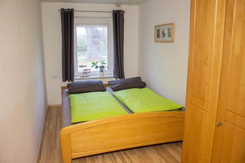 a bedroom with a bed with green pillows and a window at Ferienanlage Inselzauber in Gustow