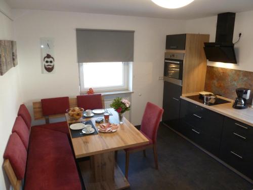 a small kitchen with a wooden table and red chairs at Ferienwohnung Ries in Nördlingen