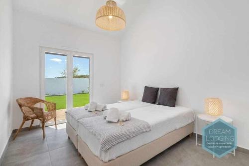 a bedroom with a bed and a chair and a window at Casa do Alto Dream Lodging in Albufeira