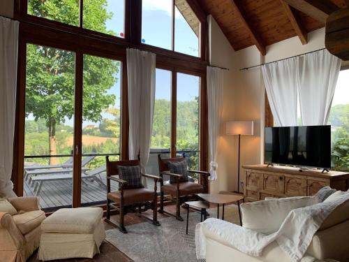 a living room with a tv and large windows at Landhaus Austria, Fehring in Fehring