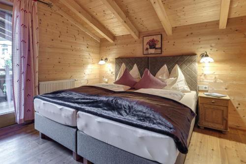 a bedroom with a large bed in a wooden room at Chalets Almdorf Zillertal, Fügen in Fügen