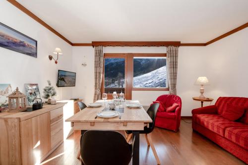 a living room with a table and a red couch at Family Apt With Superb View On The Mont Blanc in Les Houches