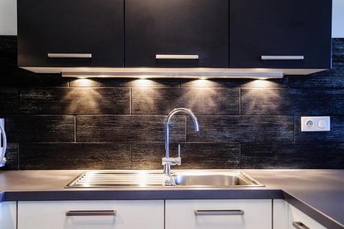 a kitchen with a sink and black cabinets at T2 PORTICCIO AGOSTA PLAGE 100M DE LA PLAGE in Porticcio