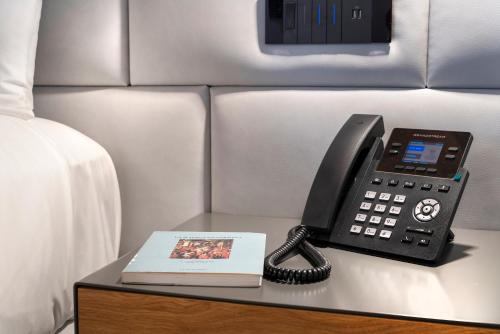 a phone and a book on a table next to a bed at Dimora Bonafede Ibla Design Rooms in Ragusa