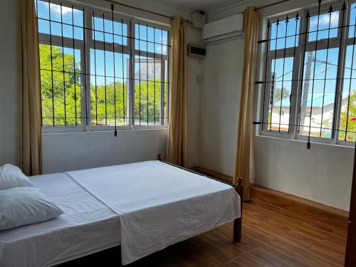 a bedroom with two windows and a bed with white sheets at Suntoo Villa Wind & Kitesurf Accommodation in La Gaulette