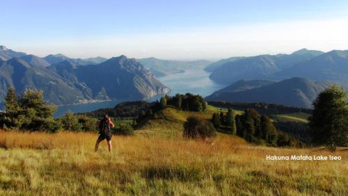 a man walking on a grassy hill overlooking a valley at Villa Glory Mountain Lake Iseo Hospitality in Bossico