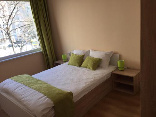 een slaapkamer met een bed met groene kussens en een raam bij Apartment Center - Stara Zagora in Stara Zagora