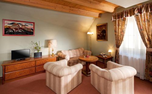 a living room with two chairs and a television at Hotel Concertino Zlatá Husa in Jindrichuv Hradec