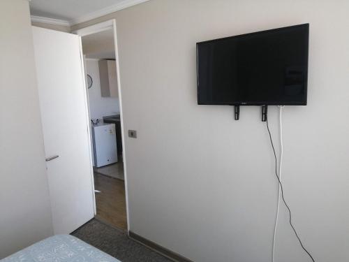 a flat screen tv hanging on a white wall at 2 Torres Calama in Calama