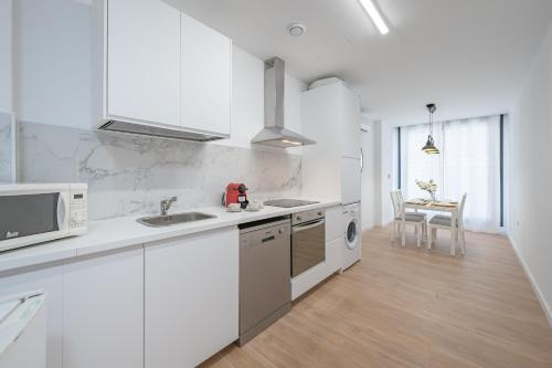 Una cocina blanca con fregadero y microondas. en Doña Elvira Malasaña, en Málaga