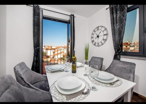 comedor con mesa, sillas y reloj en Deluxe Apartments A&A, en Rovinj