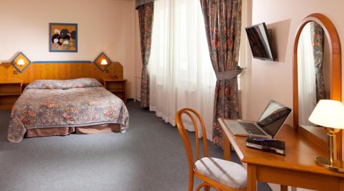 a bedroom with a bed and a desk with a laptop at Hotel Concertino Zlatá Husa in Jindrichuv Hradec