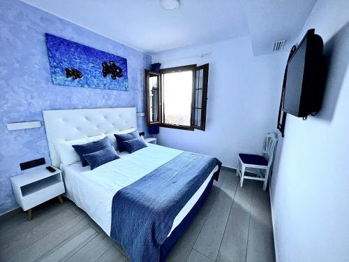 a blue bedroom with a bed and a tv at Apartamentos El Bergantin Menorca Club in Fornells