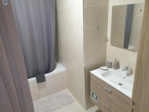 uma casa de banho com um lavatório e um chuveiro com uma cortina de chuveiro em Elite Residence 14D Praia da Rocha em Portimão