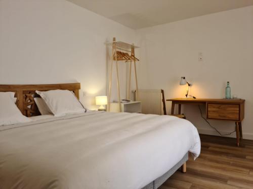 a bedroom with a large white bed and a desk at Bleu Outremer in Saint-Cast-le-Guildo