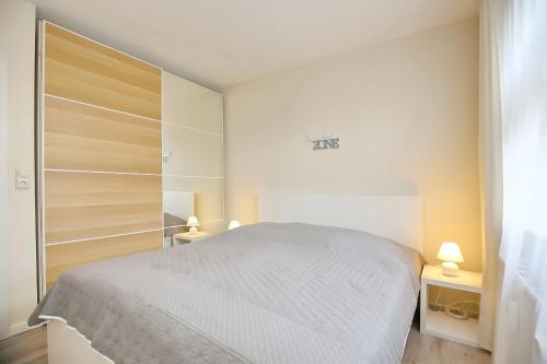 a white bedroom with a bed and a closet at Haffblick Wohnung 43 in Boltenhagen