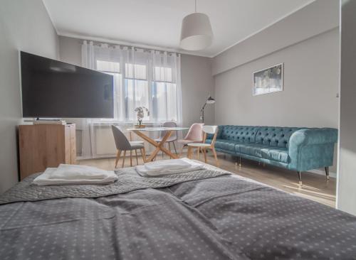 a bedroom with a bed and a couch and a table at Krosna Street Apartament in Gdańsk