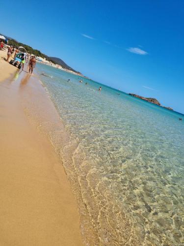 a beach with a group of people in the water at Martina's Place (with panoramic views) in Chia
