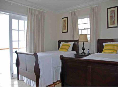 a bedroom with two beds and two windows at Bianca Bay 3 Bedroom West Coast Beach Front Villa in Saint James