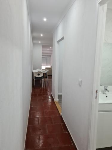 un couloir avec une chambre dotée d'un lavabo et d'une table dans l'établissement Casa do Mestre, à Setúbal