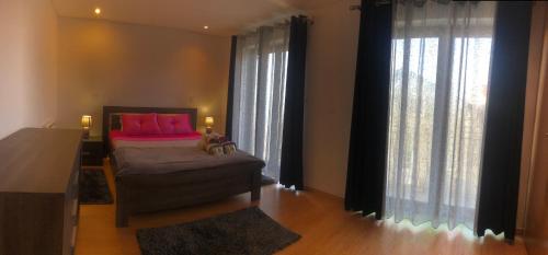 a bedroom with a bed with pink pillows and curtains at Casa do Palheiro in Pitões das Júnias