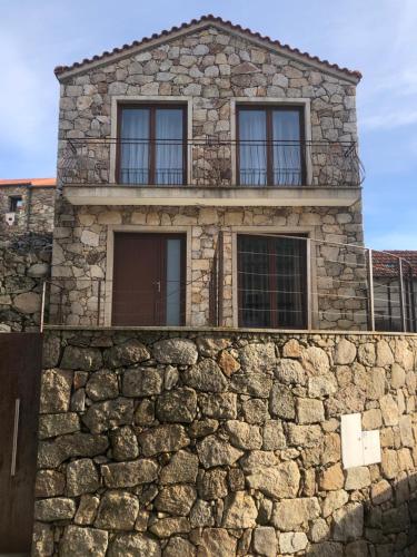 een stenen gebouw met ramen op een stenen muur bij Casa do Palheiro in Pitões das Júnias