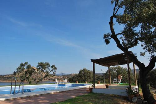 a swimming pool with a pavilion next to a tree at Finca La Vicaria ROMERO in Zufre