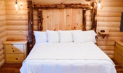 ein Schlafzimmer mit einem weißen Bett in einem Blockhaus in der Unterkunft Treehouse #6 by Amish Country Lodging in Millersburg