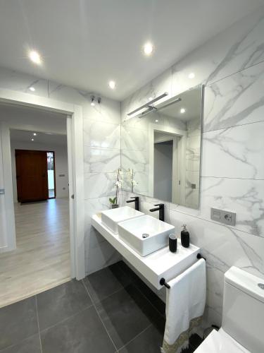 a white bathroom with a sink and a mirror at Apartamentos el Oligo in Cadavedo