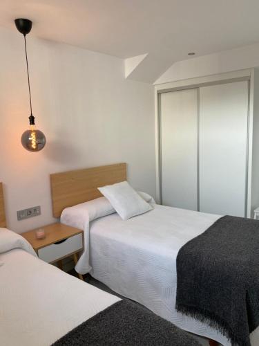 a hotel room with two beds and a lamp at Apartamentos el Oligo in Cadavedo
