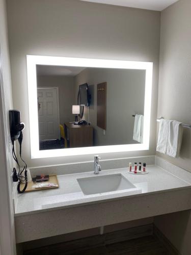 a bathroom with a sink and a large mirror at Days Inn by Wyndham Lake Charles in Lake Charles