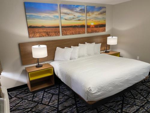 a hotel room with a bed and three paintings on the wall at Days Inn by Wyndham Lake Charles in Lake Charles