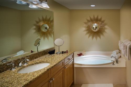 a bathroom with two sinks and a tub with two mirrors at Escapes! To The Shores Orange Beach, A Ramada by Wyndham in Orange Beach