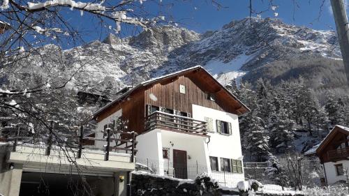 a house in the snow with a mountain in the background at Villa Bianca Bormio garden and parking in Premadio